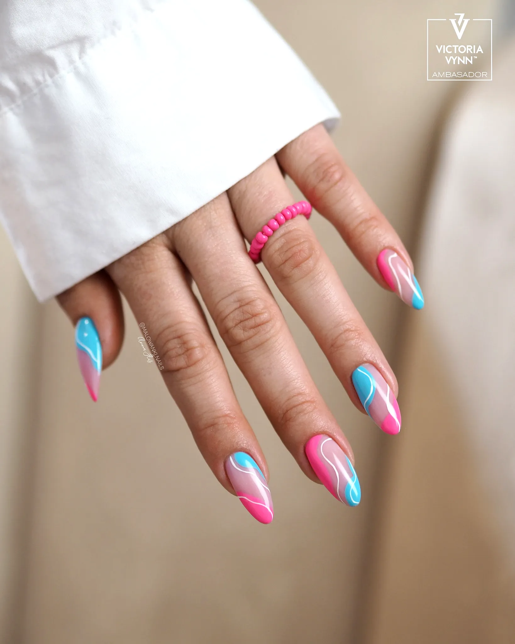 Elegant stiletto swirl nail designs in vibrant pink and blue with a glossy finish and dynamic patterns