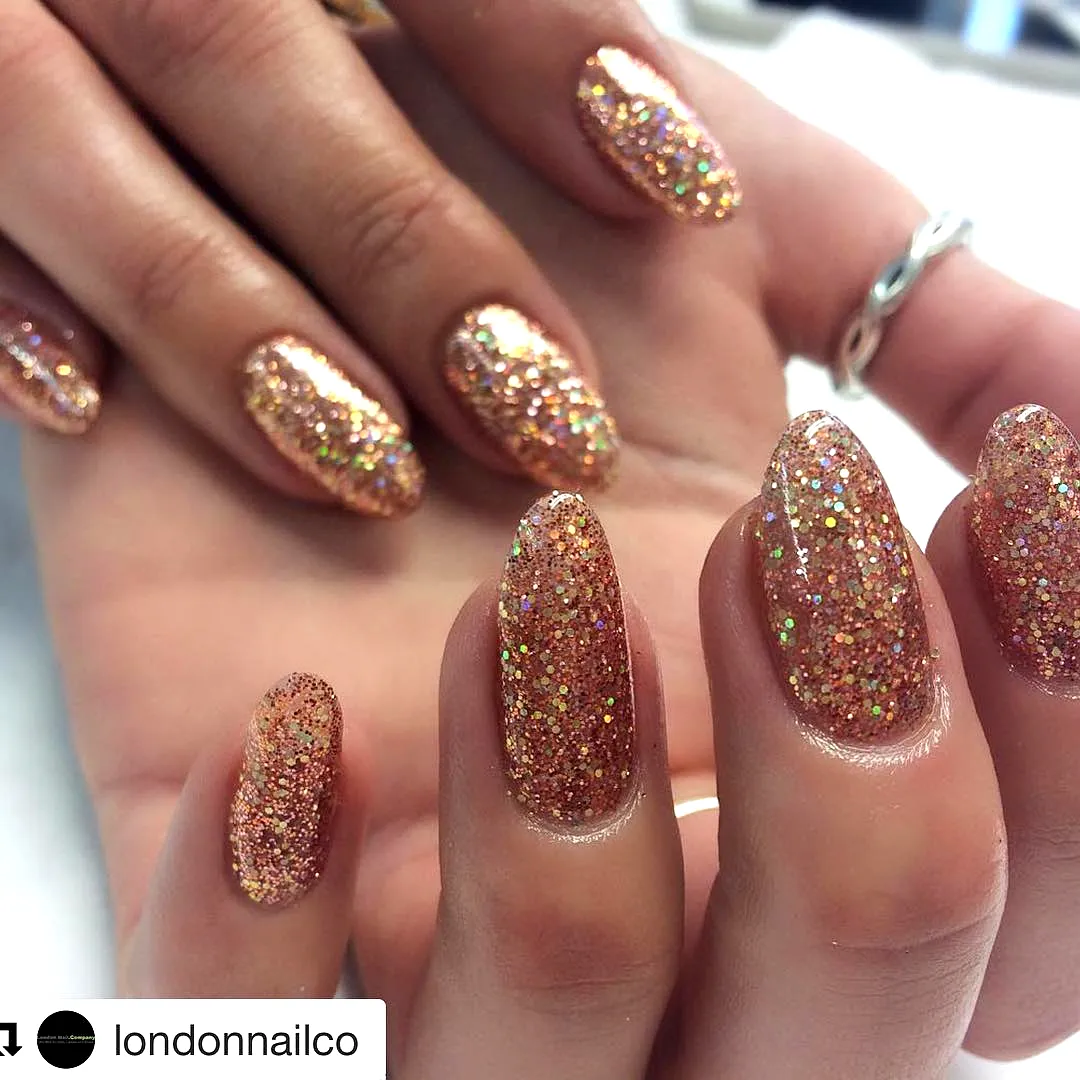 Glamorous Almond Shaped Rose Gold Nails with Glittery Holographic Embellishments