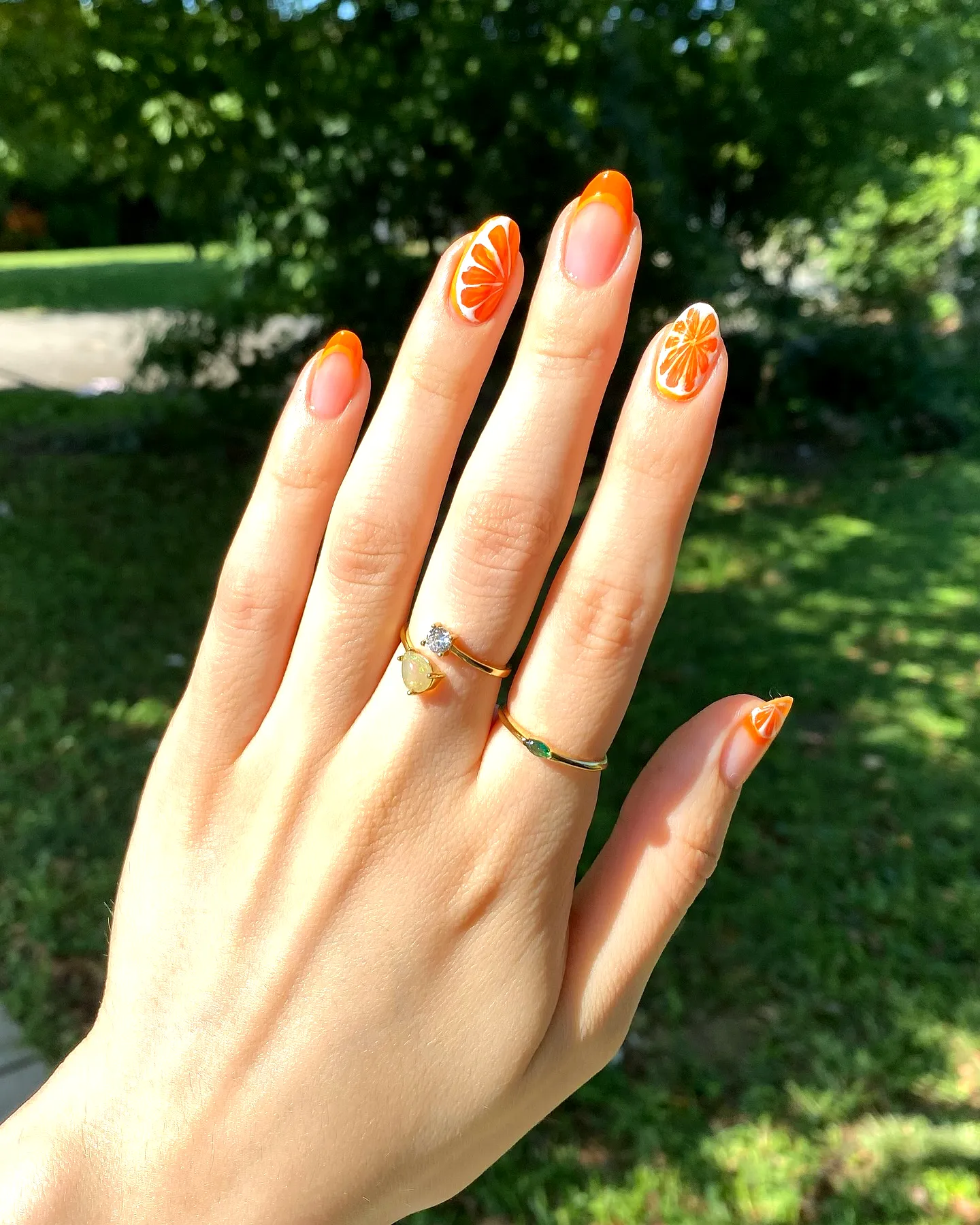 Playful Almond Shaped Orange Nails with White Floral Patterns and Glossy Finish