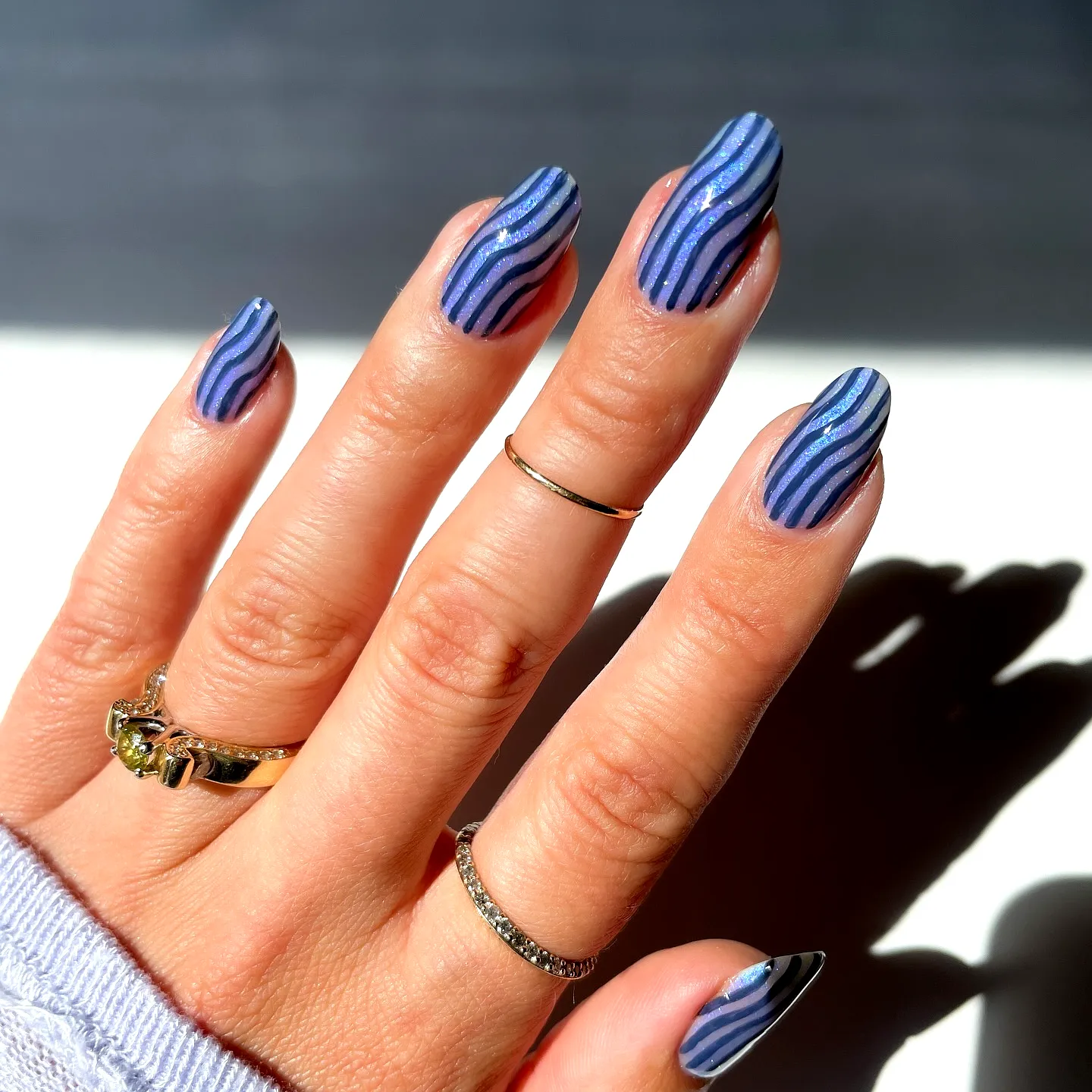 Sleek Almond Shaped Striped Nails in Blue and Purple with Shimmer and Gold Rings