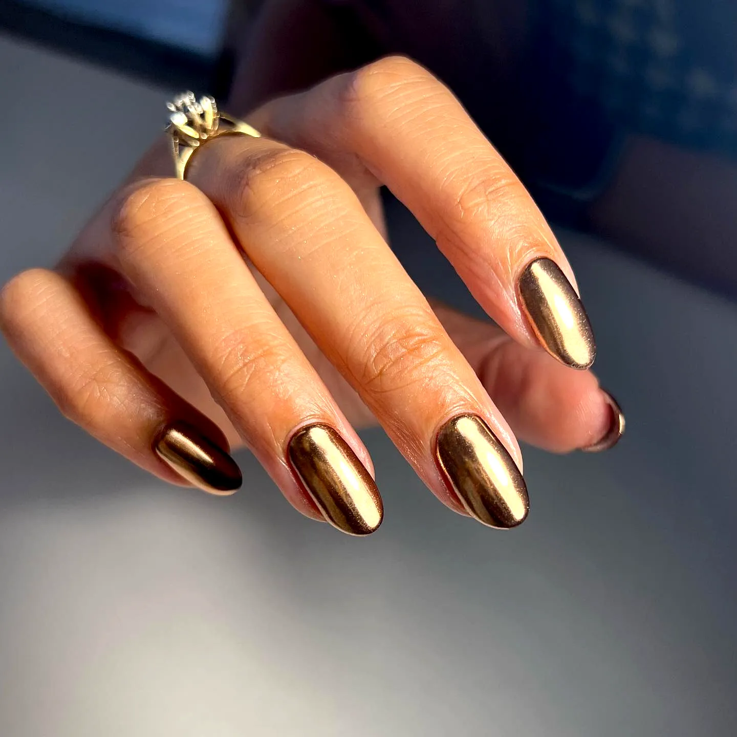 Sleek elongated almond-shaped gold chrome nails with a glossy metallic finish