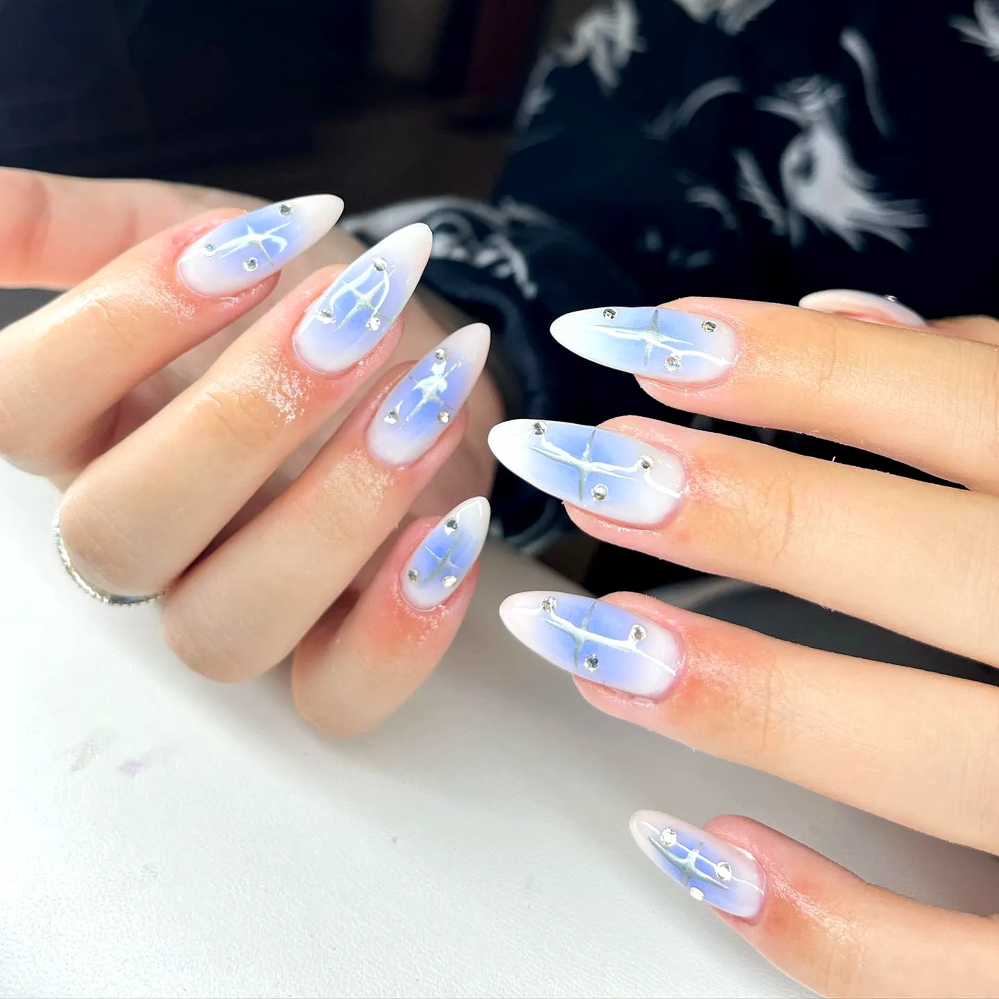 Stunning Almond-Shaped Aurora Nails with Gradient Blue and White Ombre and Elegant Silver Studs