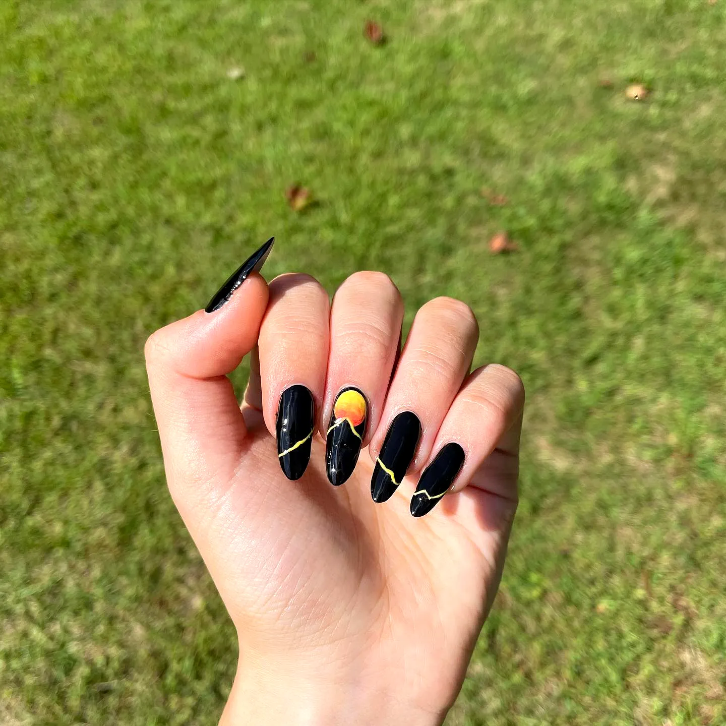 Stunning Almond Shaped Mountain Nails with Black and Gold Accents and Vibrant Sunset Gradient