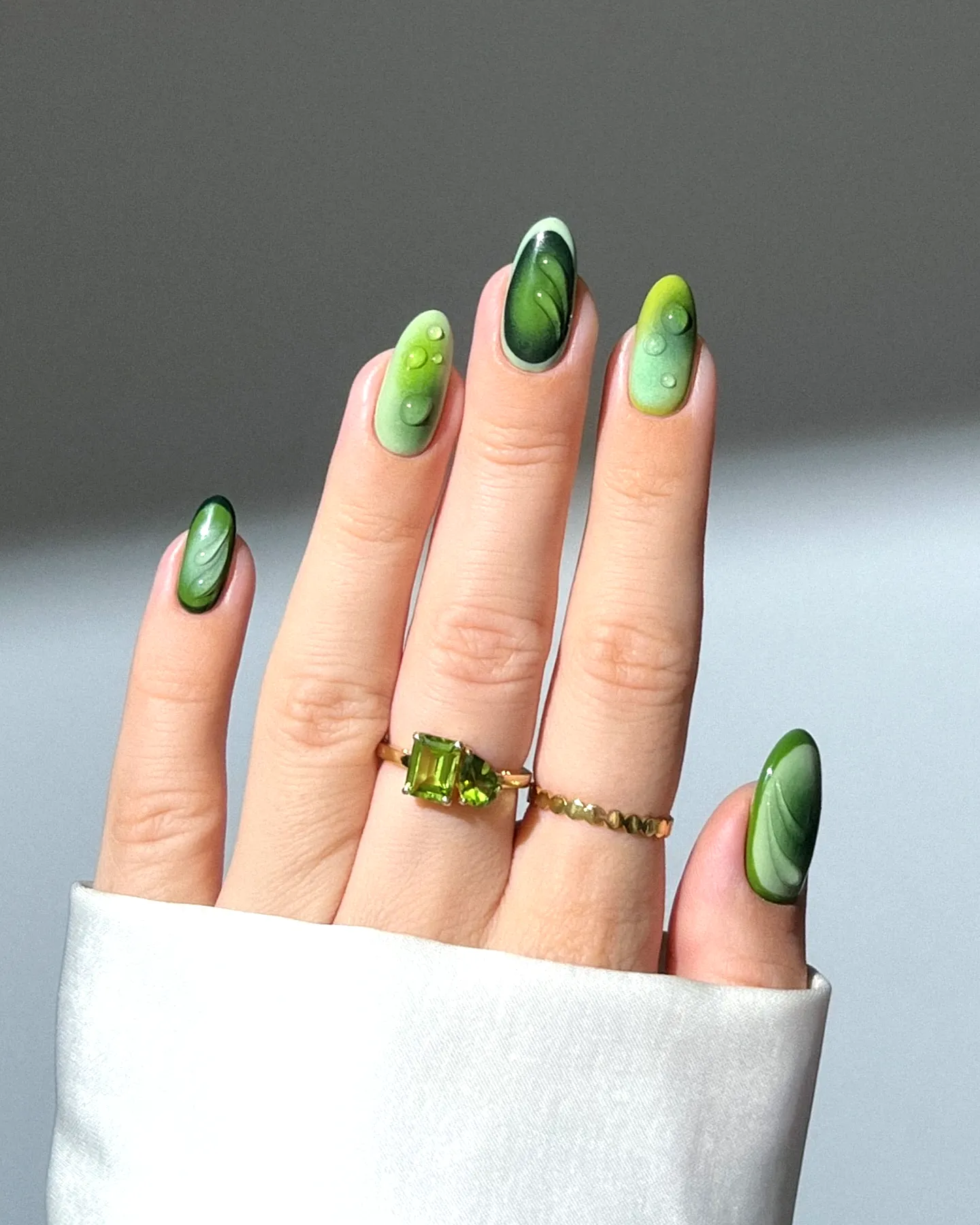 Stylish Almond Shaped Green Nails Featuring Marble Art and Glossy Accents