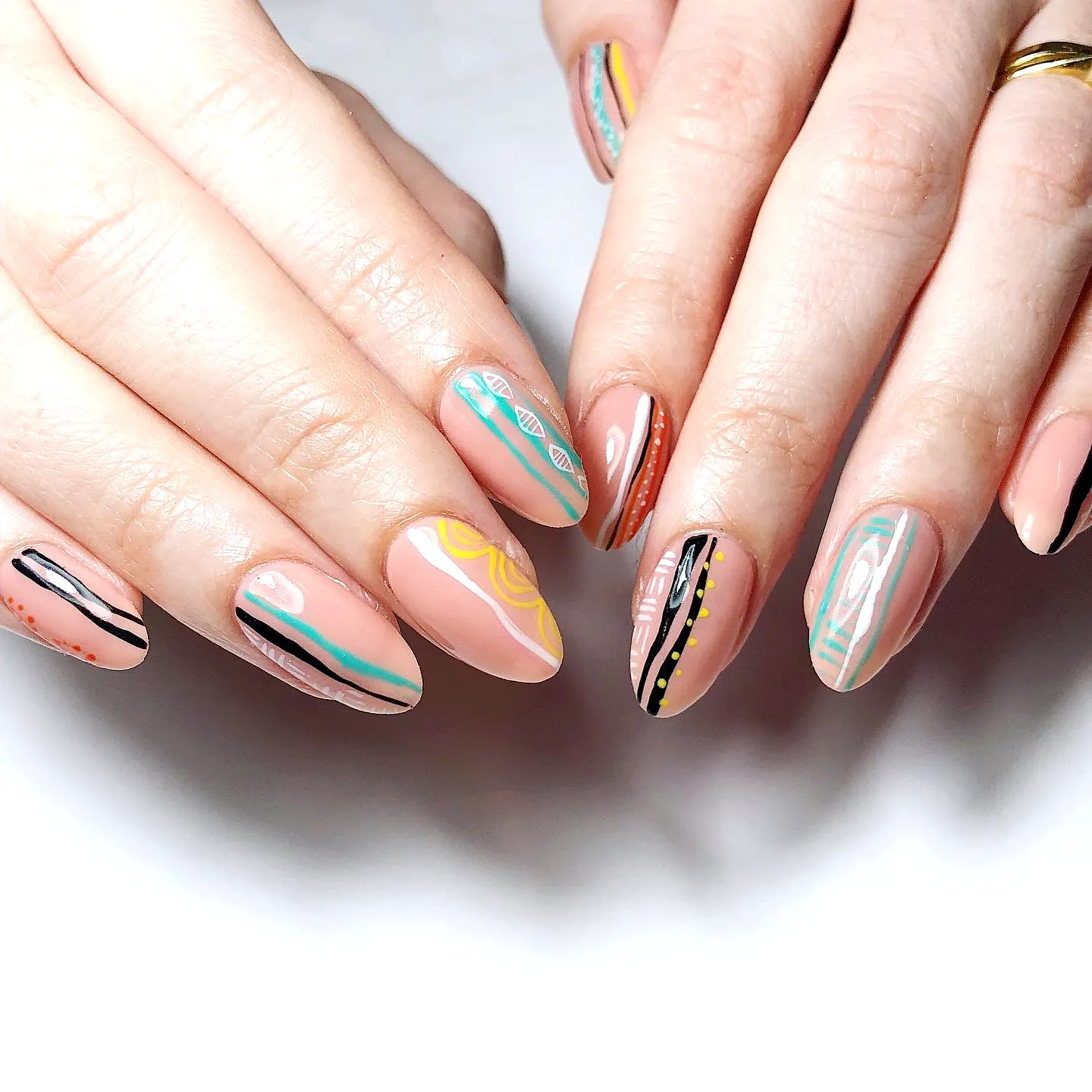 Stylish Almond Shaped Travel-Inspired Nails with Abstract Patterns in Peach and Turquoise