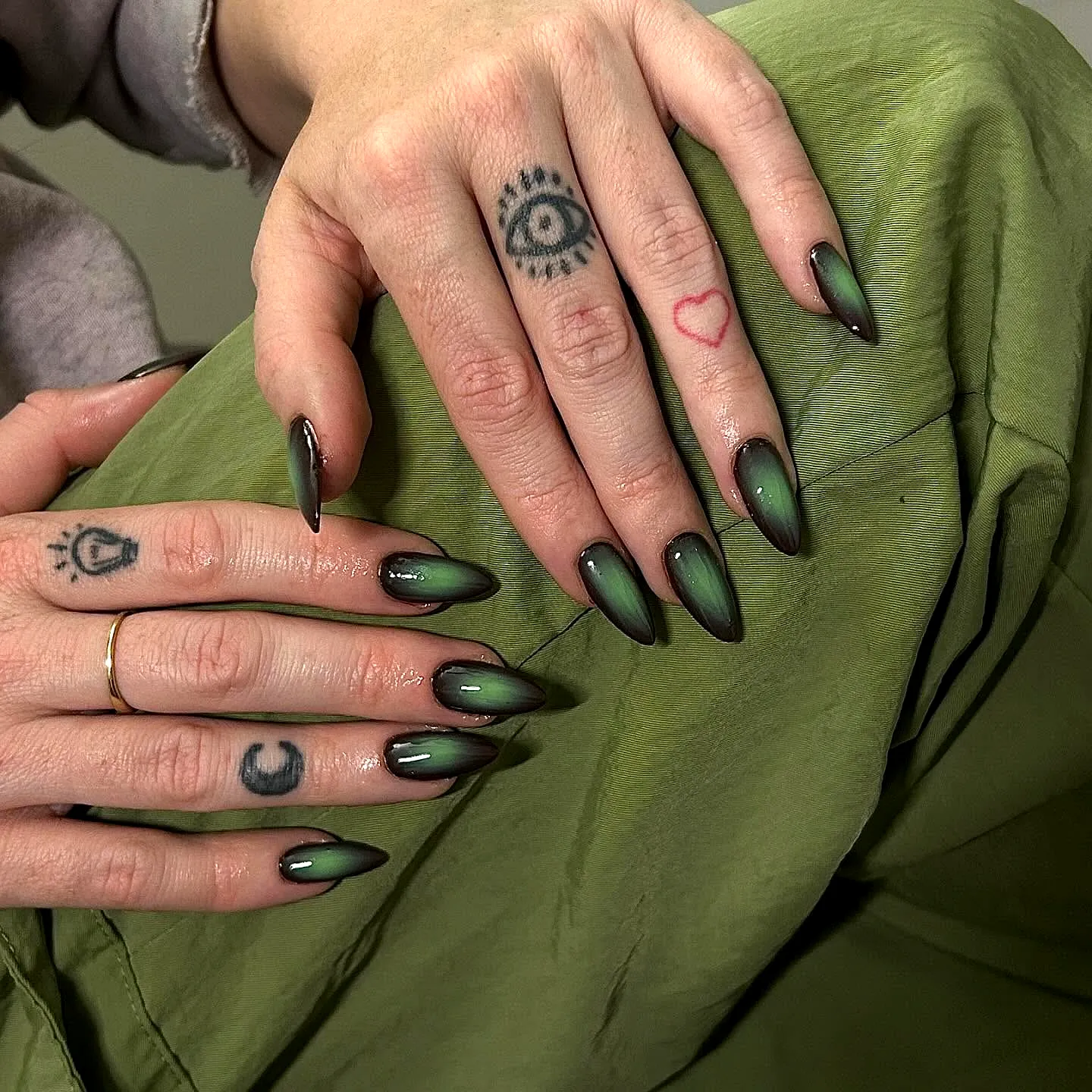 Trendy Almond-Shaped Green Nails with Ombre Effect and Modern Tattoo Art