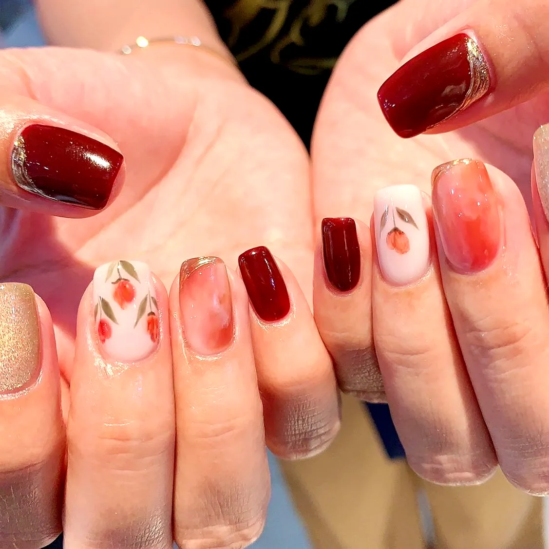Tulip Nail Designs Featuring Square-Shaped Nails in Deep Red and Soft Nude with Elegant Floral Patterns and Metallic Gold Accents