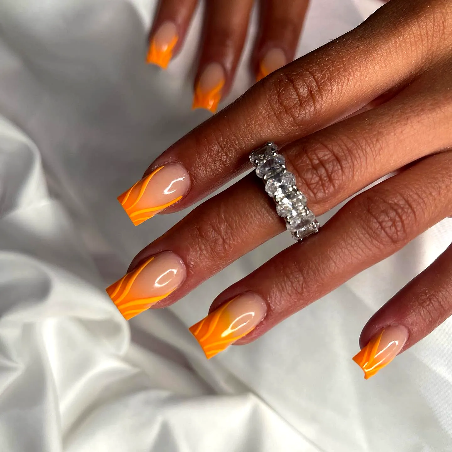 Vibrant Orange Square Nails with Wavy Gradient Design and Elegant Hand Jewelry