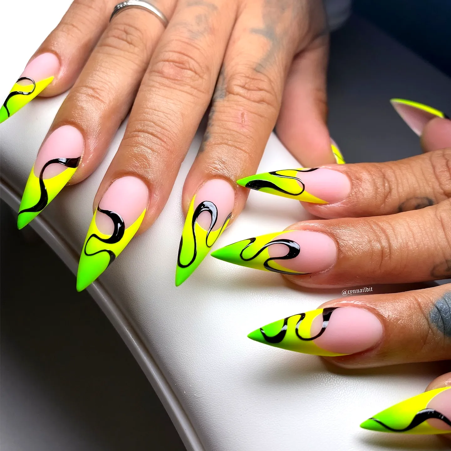 Vibrant Stiletto Neon Nails with Swirling Black Accents and Soft Pink Highlights
